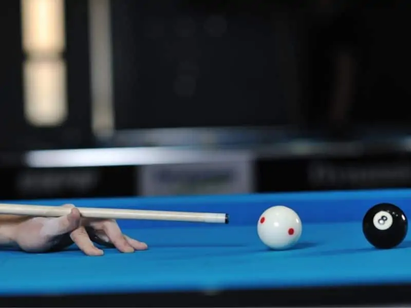 Person striking cue ball on billiard table