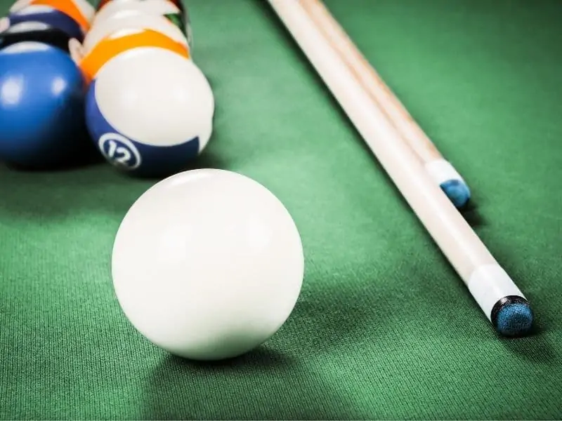 Cue ball and tips of cue sticks on a pool table