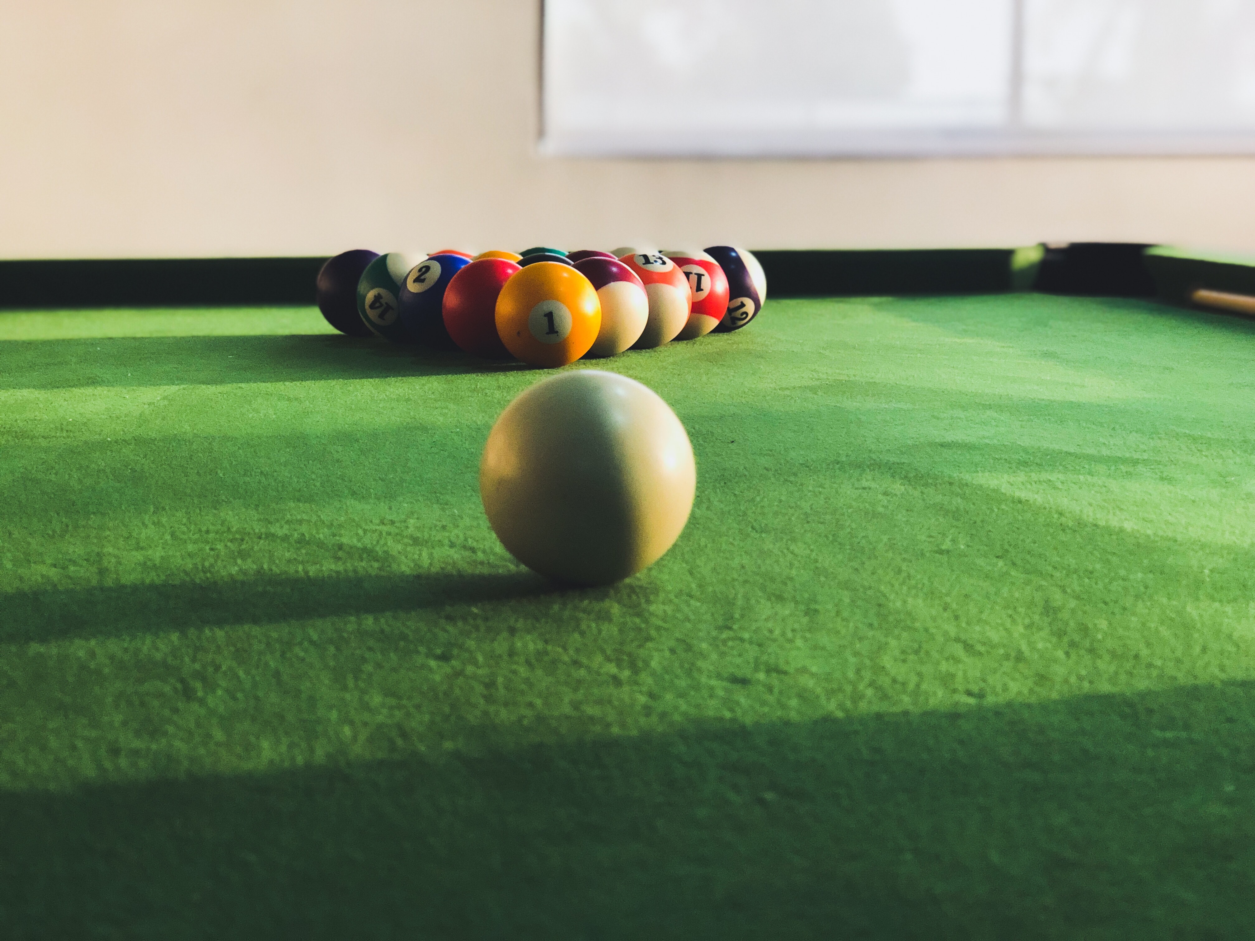 Racked pool balls and cue on pool table