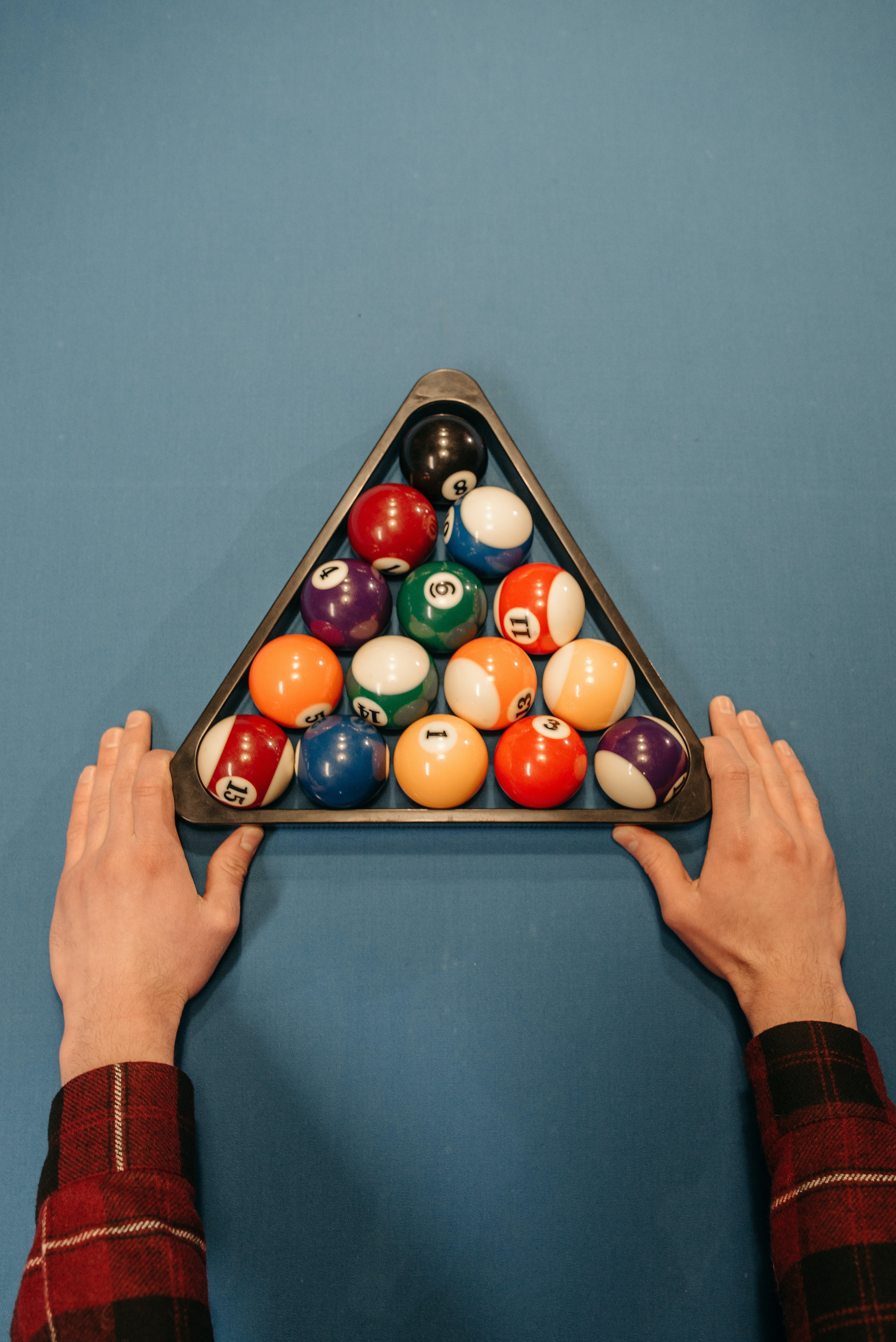 A rack of billiard balls with cue stick and cue ball