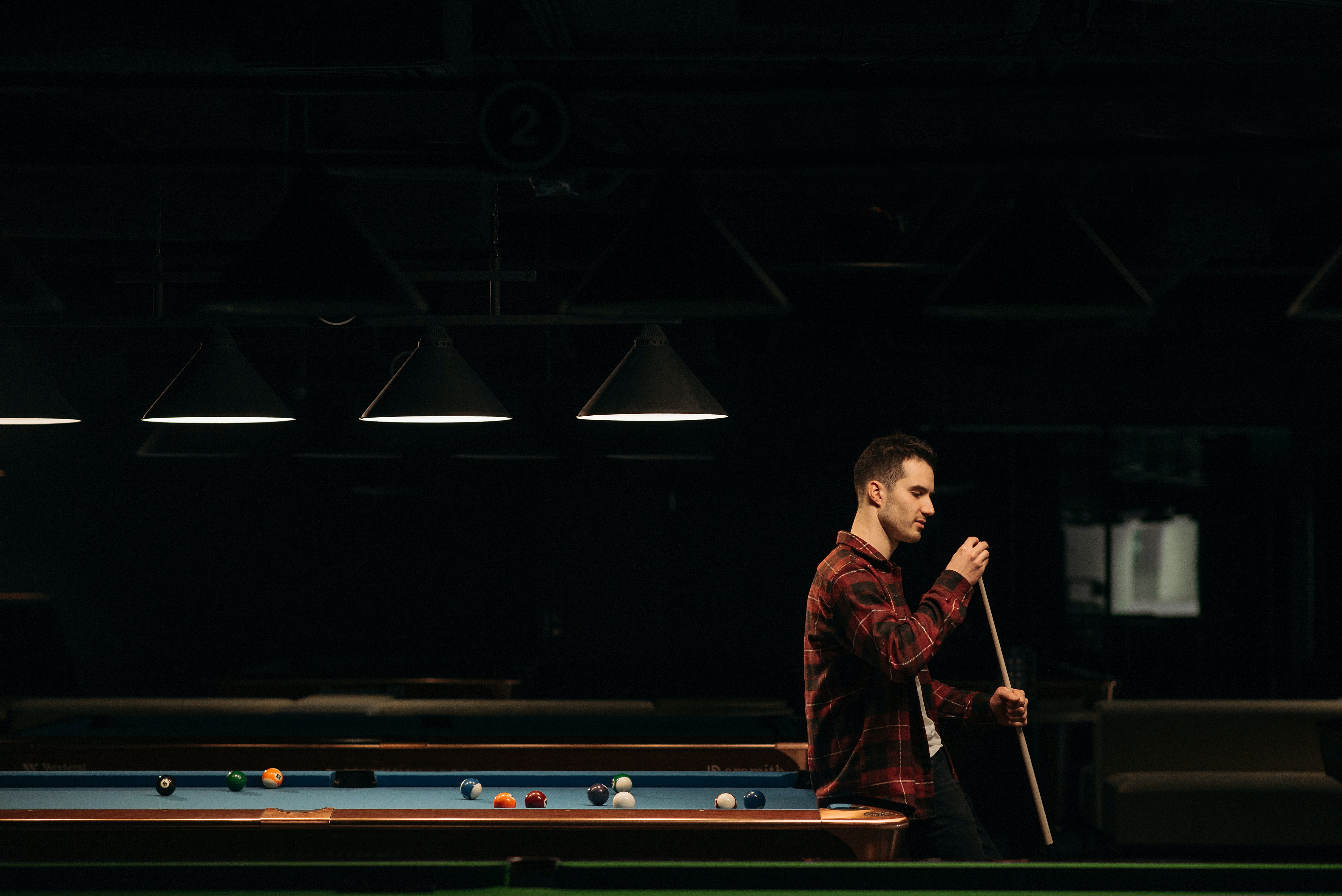 Man chalking cue while playing billiards solo